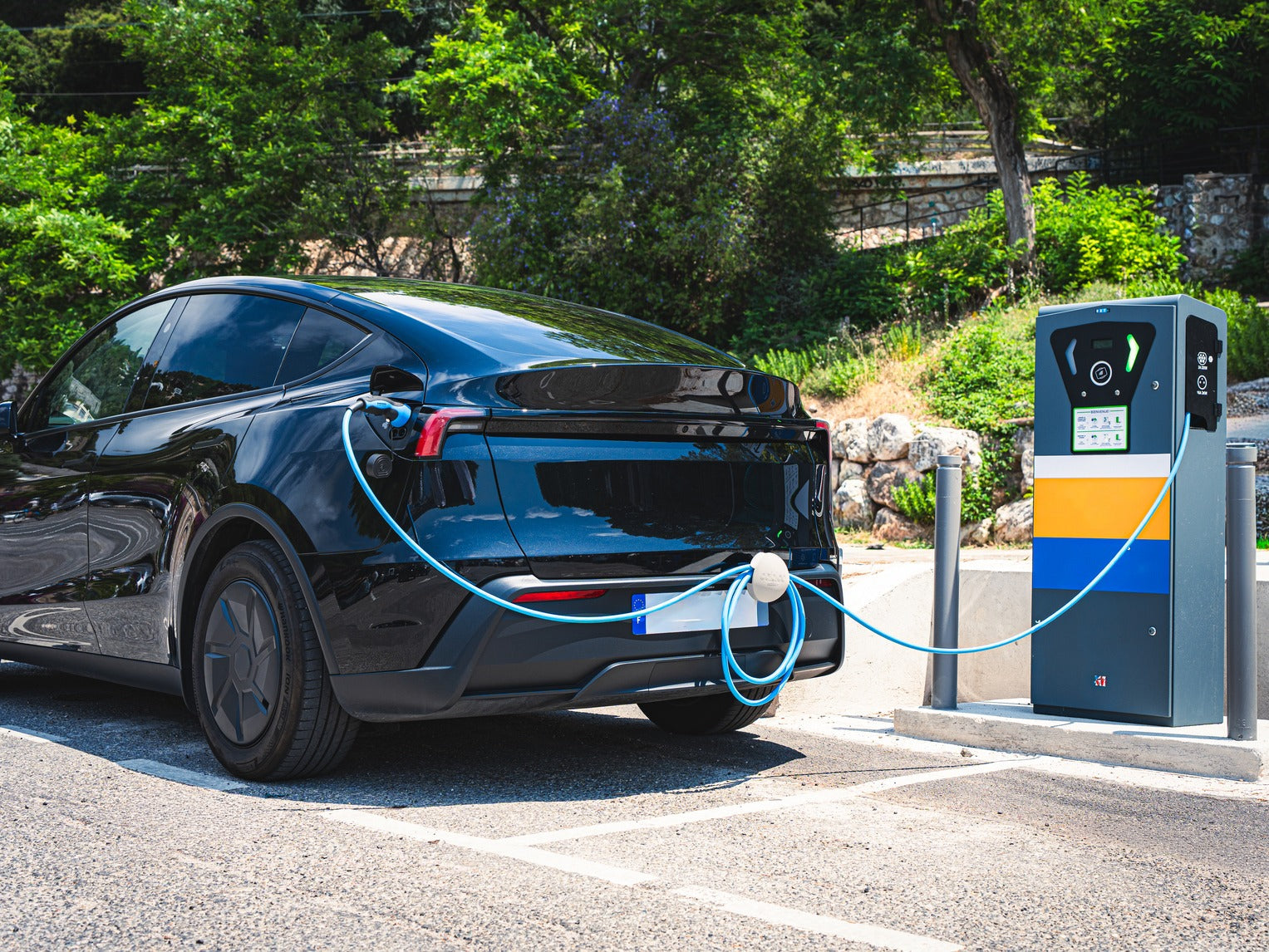 Protection du câble de recharge maintenu hors du sol par un support pendant la charge d'une voiture électrique